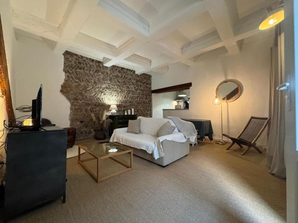 a living room with a white couch and a stone wall at El Niu - Perpignan hyper centre in Perpignan
