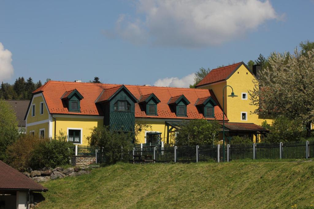 a large yellow house with red roofs on a hill at Ferienwohnung Zum alten Forsthaus in Messern