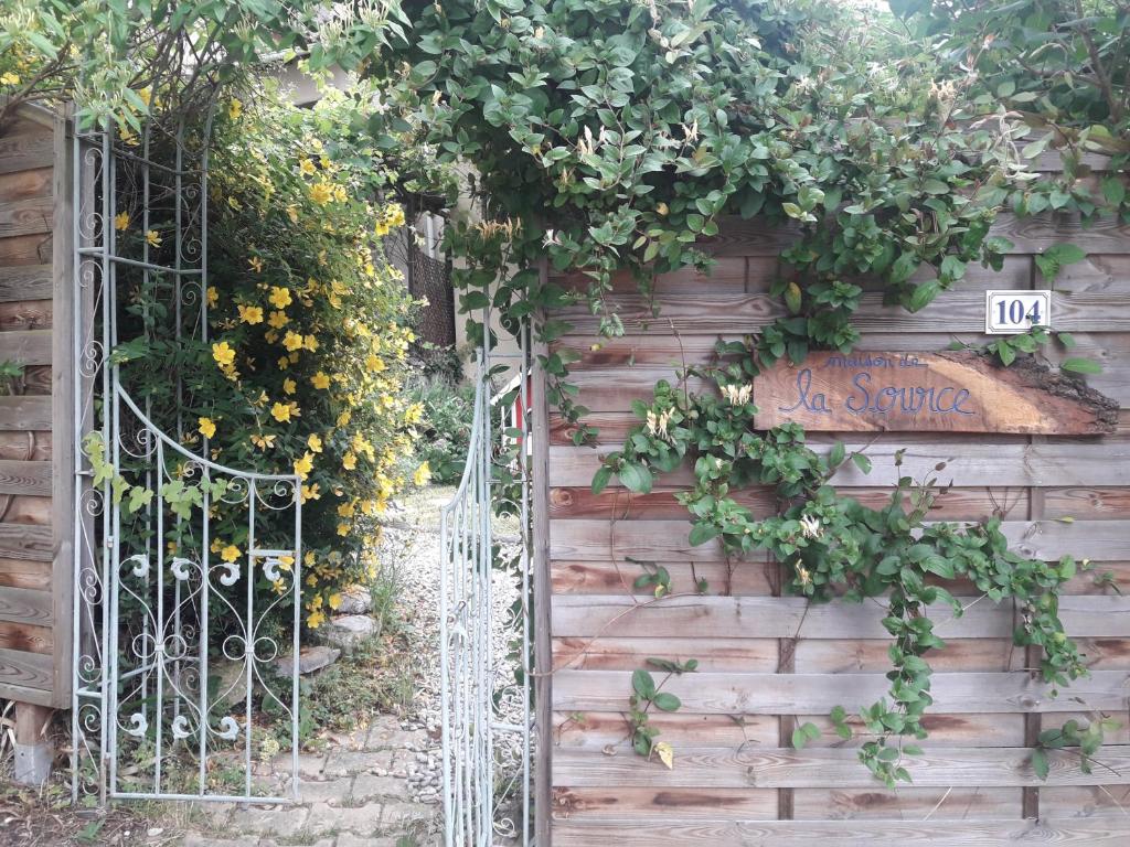 an entrance to a garden with a gate and flowers at Maison de la Source in Leychert