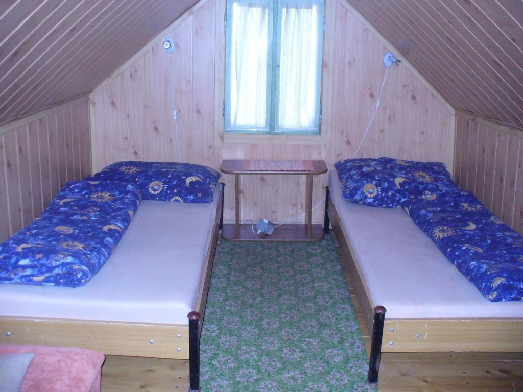 2 łóżka w niewielkim pokoju z drewnianymi ścianami w obiekcie Chalupa na lazoch w mieście Nová Baňa