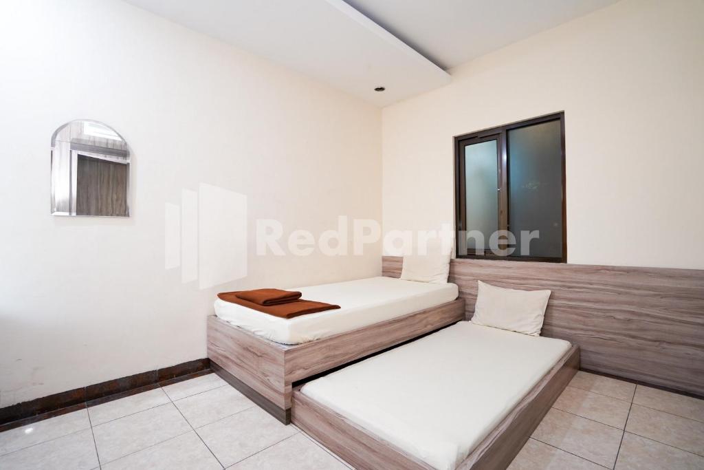 two beds in a room with a window at Griya Borobudur Malang Syariah RedPartner in Blimbing