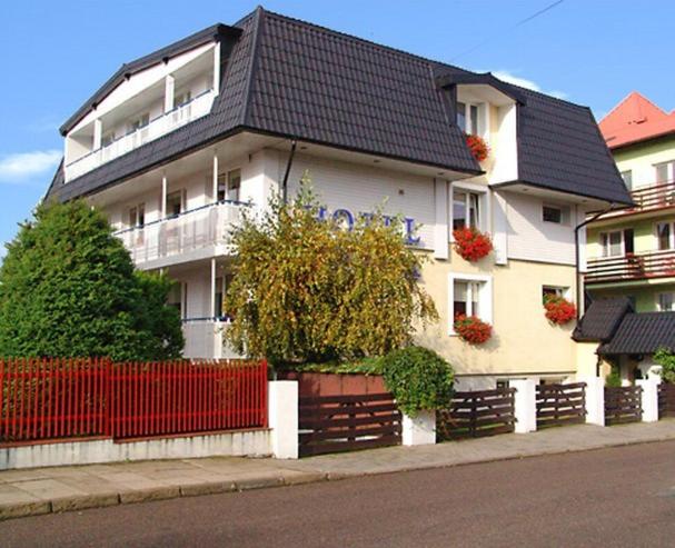 a white house with a red fence in front of it at Hotel Europa in Jastrzębia Góra