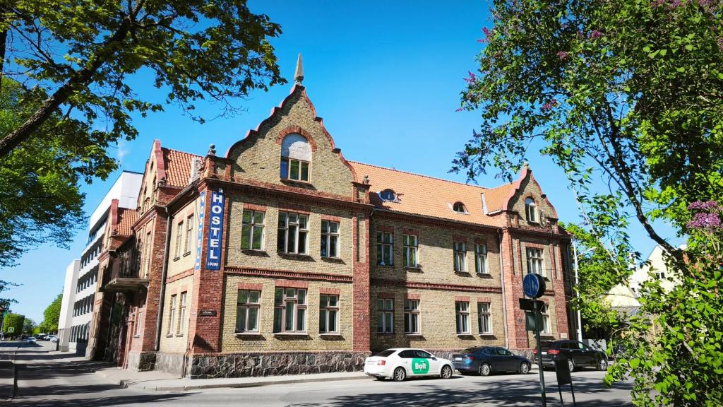 an old building on a street with cars parked in front at Hostel Lõuna in Pärnu