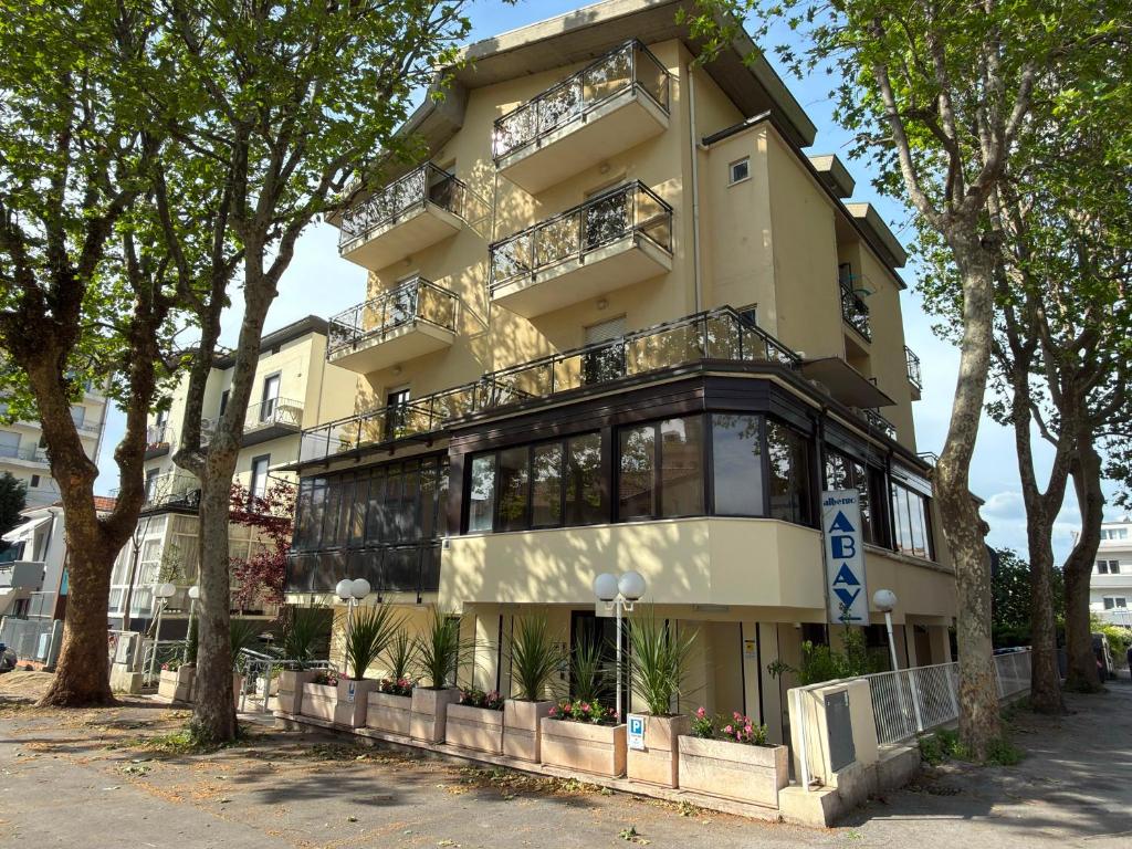 a tall building with balconies and trees in front of it at Hotel Abay in Rimini