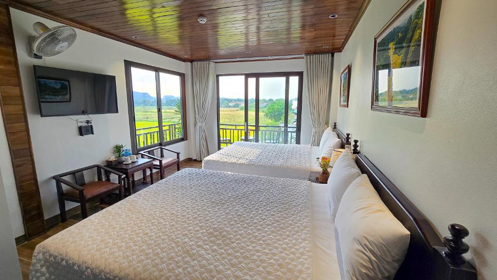 a bedroom with two beds and a large window at Tam Cốc Hà Anh Hotel in Văn Lâm