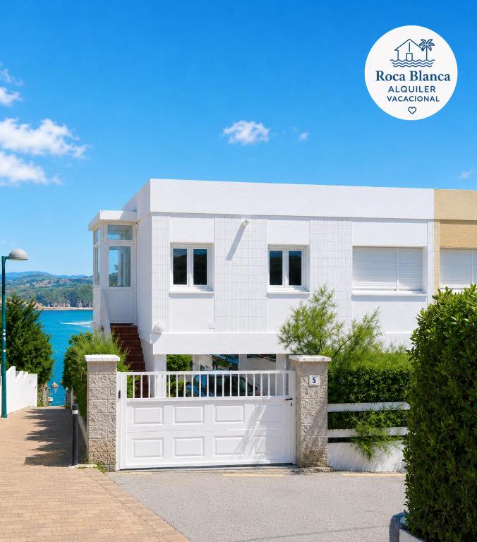 a white house with a white garage gate at Casa Roca Blanca Suances in Suances
