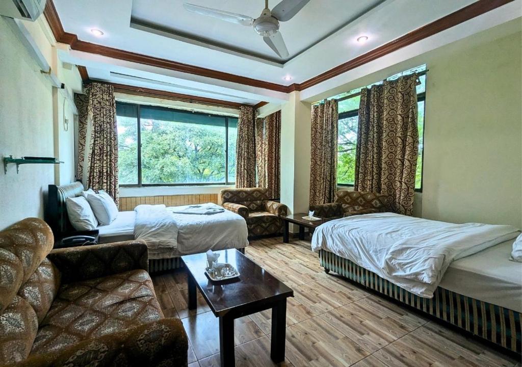 ein Hotelzimmer mit zwei Betten und einer Couch in der Unterkunft New Islamabad Hotel in Islamabad