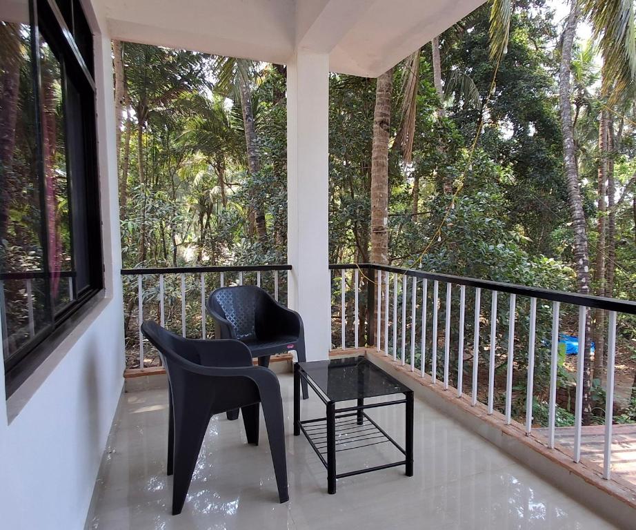 a porch with two chairs and a table and a window at Rooms In Canacona in Canacona
