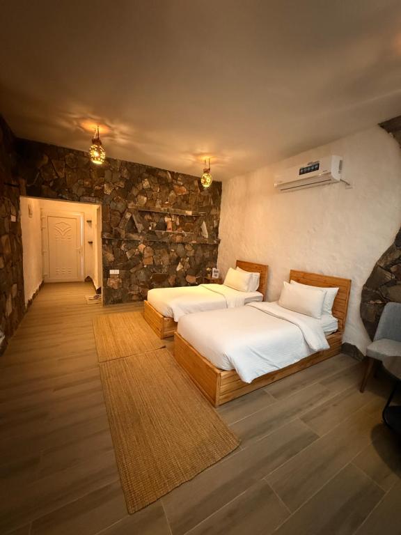 a bedroom with two beds and a stone wall at Panorama Guest House Jabal Shams in Sa‘ab Banī Khamīs
