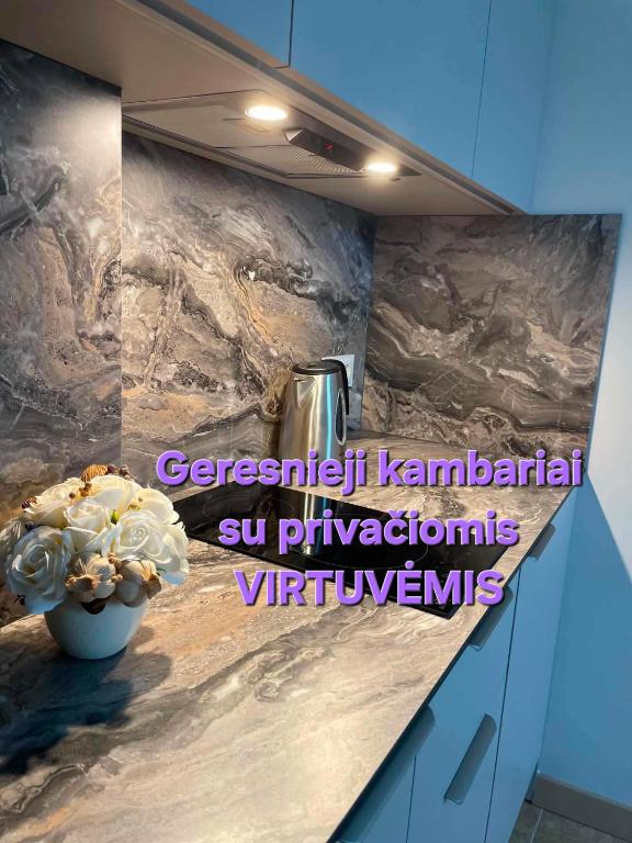 a kitchen counter with a vase of flowers on it at Vila Uosis in Palanga