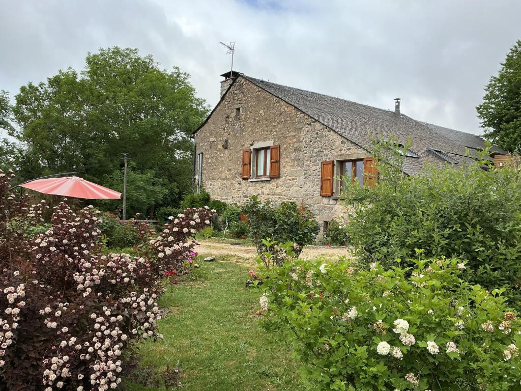 a stone house with an umbrella in the garden at Chez Rose-Laure in Grandviala