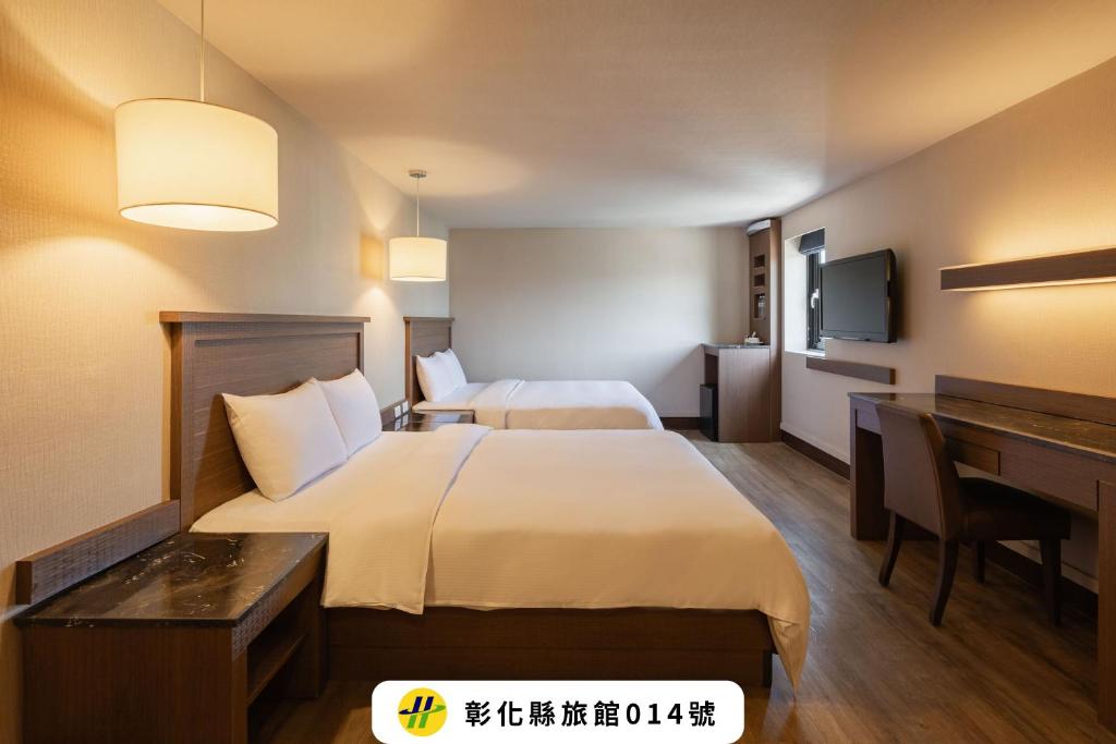 a hotel room with two beds and a desk at Kindness Hotel - Yuanlin Branch in Yuanlin