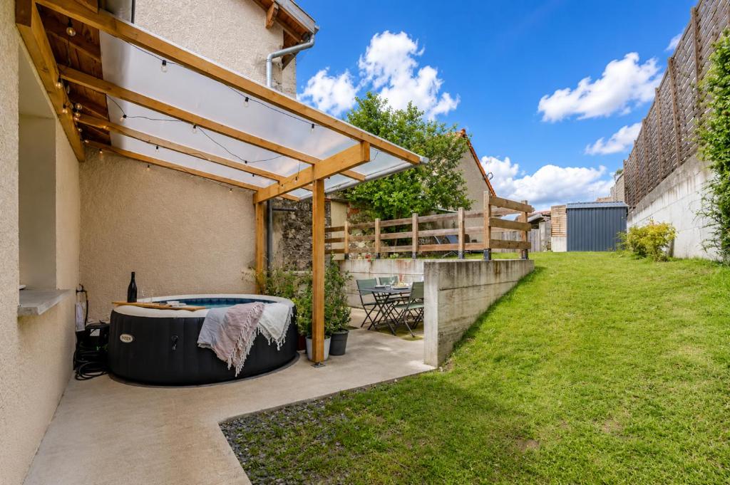 a backyard with a hot tub and a wooden pergola at Comme à la maison ! in Matour