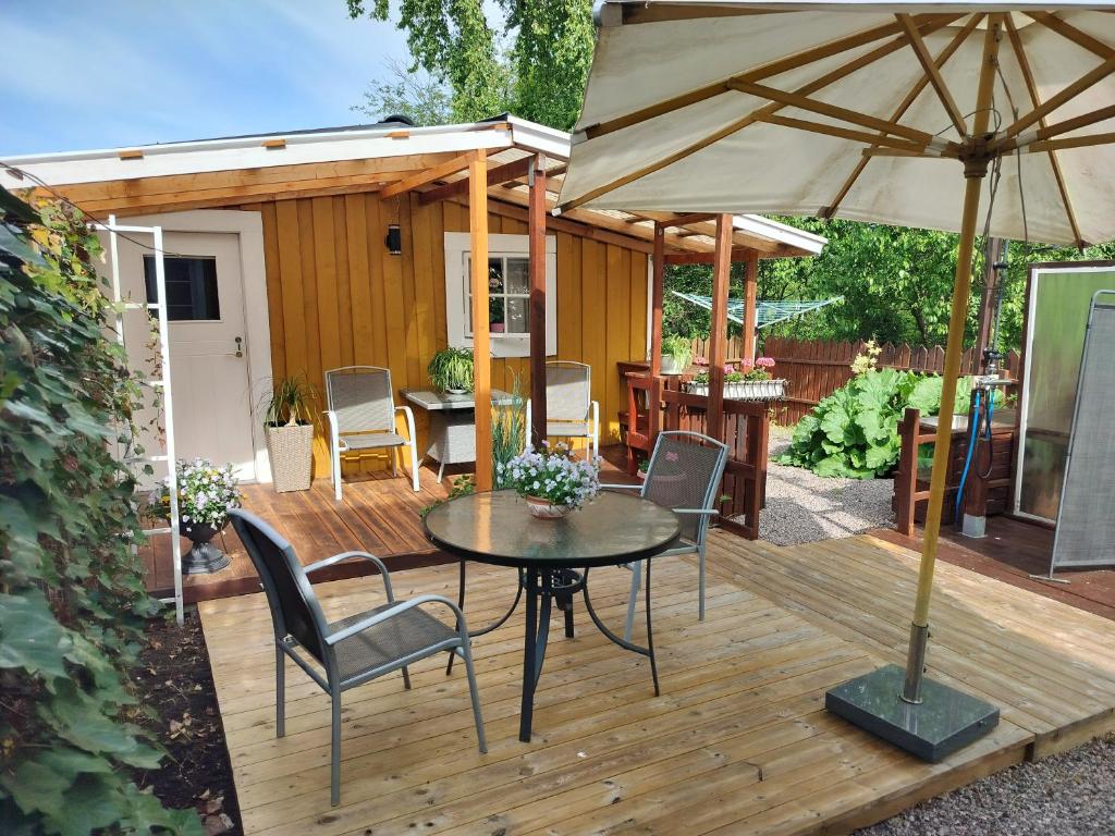 a wooden deck with a table and an umbrella at Lilla Stugan, Sjötorp in Sjötorp