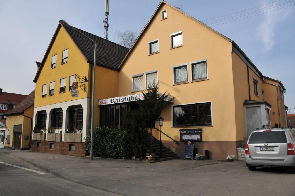 a yellow house with a car parked in front of it at Hotel Gasthof Ratstube in Kirchheim unter Teck