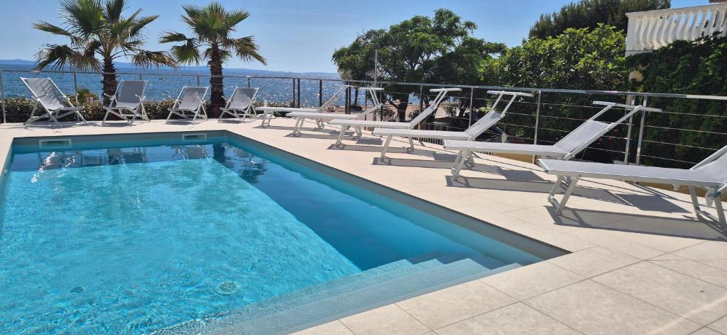 a swimming pool with chaise lounge chairs and the ocean at Dinary Penthouse apartment in Vir