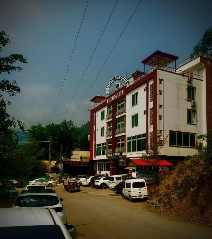 a large building with cars parked in a parking lot at Bridge Residency in Muzaffarabad