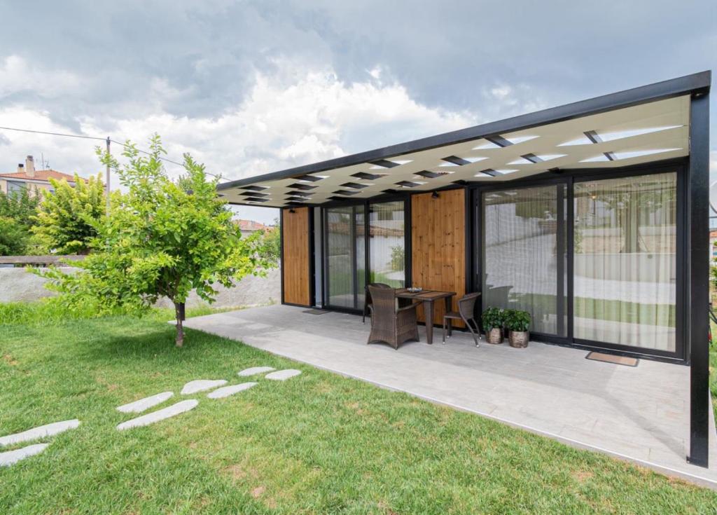a house with a patio with a table and a tree at Morera Suite Paliouri in Paliouri