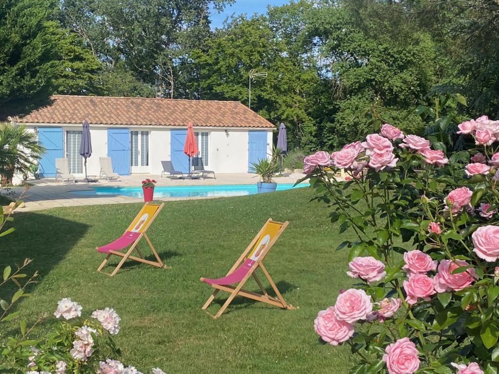 two chairs in a yard with a house and roses at Gîte des Petites Fadettes "MELUSINE" in Lannepax