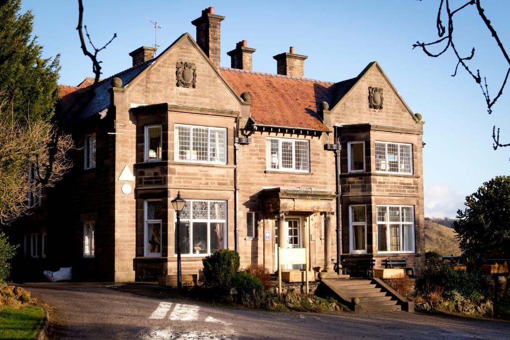 a large brick house with white windows on a street at YHA Ravenstor in Millers Dale