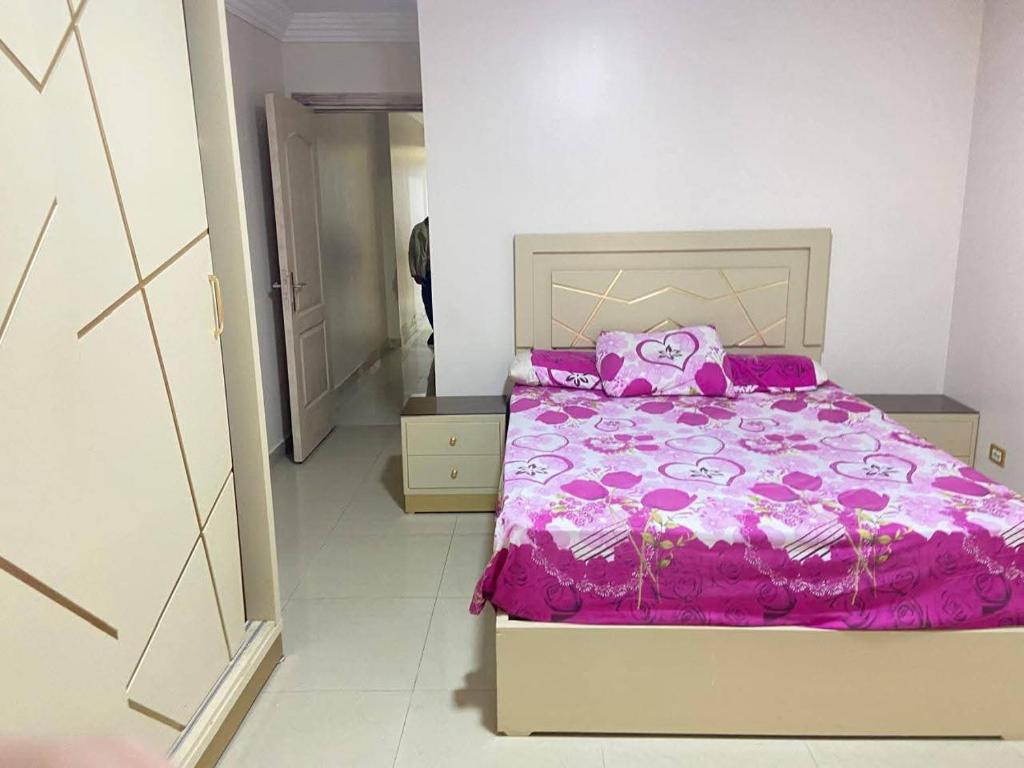 a bedroom with a bed with a pink blanket at Vera home in Kafr al Ishārah