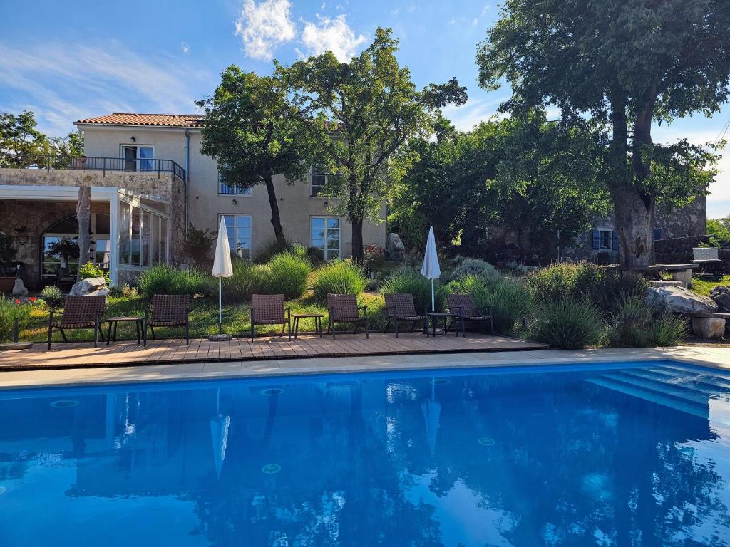 a pool with chairs and umbrellas next to a house at Boutique Resort OSMA - Adults Only in Malinska