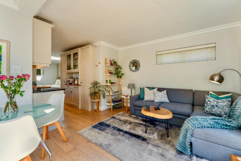 a living room with a blue couch and a table at Fig Tree Cottage - Leafy Constantia Cottages in Cape Town