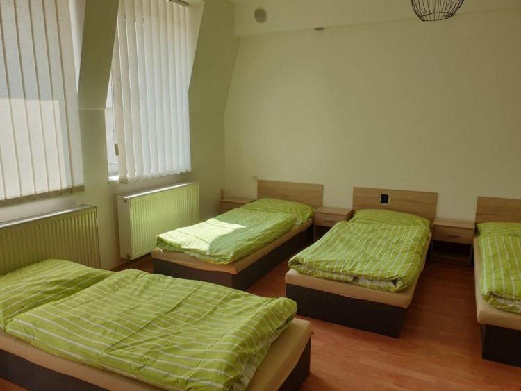 a room with three beds with green sheets on them at Ubytování Klicperova in Chlumec nad Cidlinou