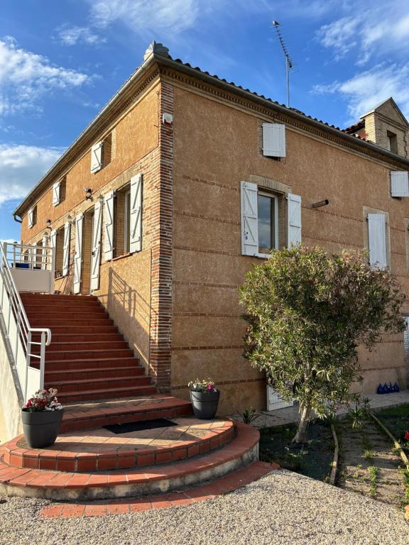 a brick house with stairs in front of it at chambres d'hotes des capellas in Bessens