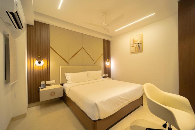 a bedroom with a white bed and a white chair at Sawariya Hotels in Tiruvannāmalai