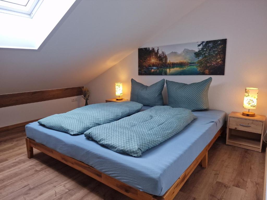 a bedroom with a bed with blue sheets and two lamps at Ferienwohnung Okami-Familie Bernöcker in Fischbachau