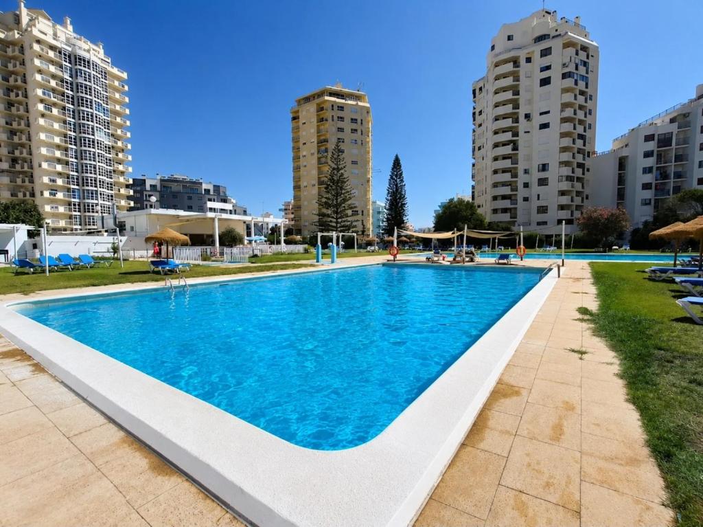 a large swimming pool in a city with tall buildings at Apartamento Davasa in Armação de Pêra