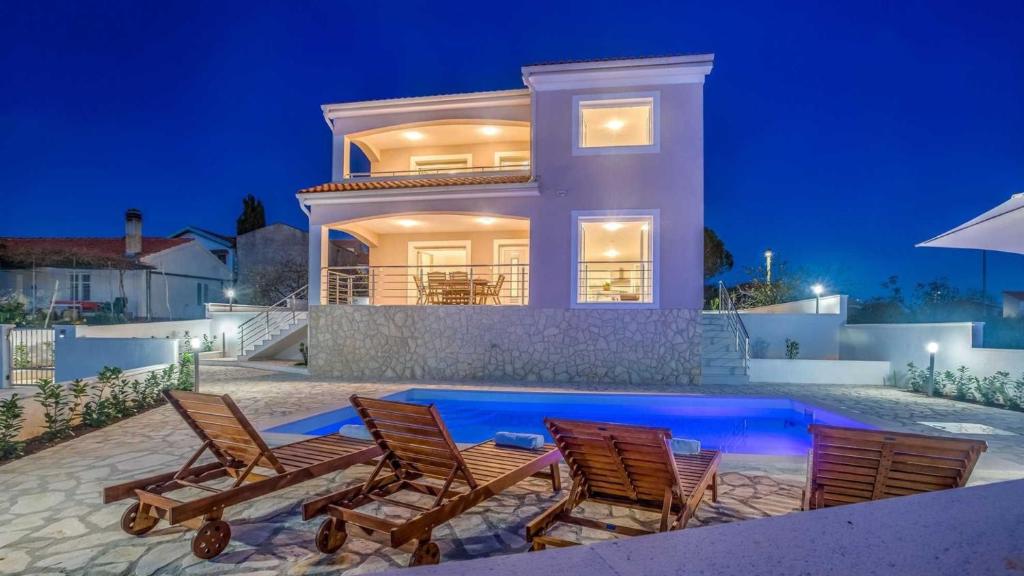 a villa with a swimming pool at night at Villa Isabella by Villas Guide in Malinska