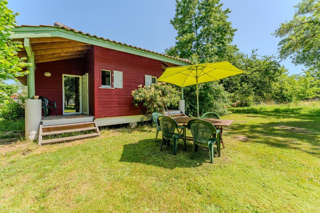 a table and chairs with a yellow umbrella in front of a house at Le Cabanon Mios in Mios