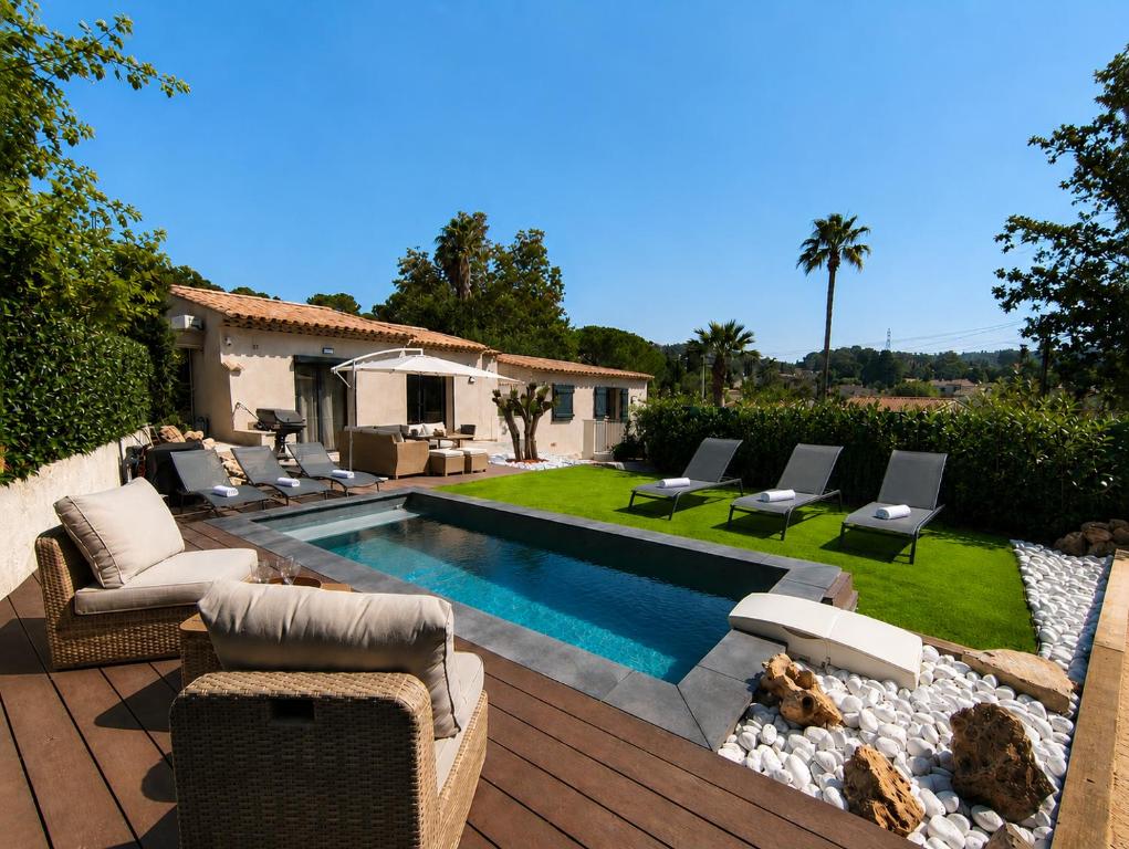 a backyard with a pool and chairs and a house at La petite maison in Mougins