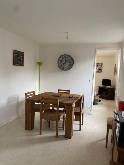 a dining room table with chairs and a clock on the wall at Ferme des hospices in La Celle-sous-Gouzon