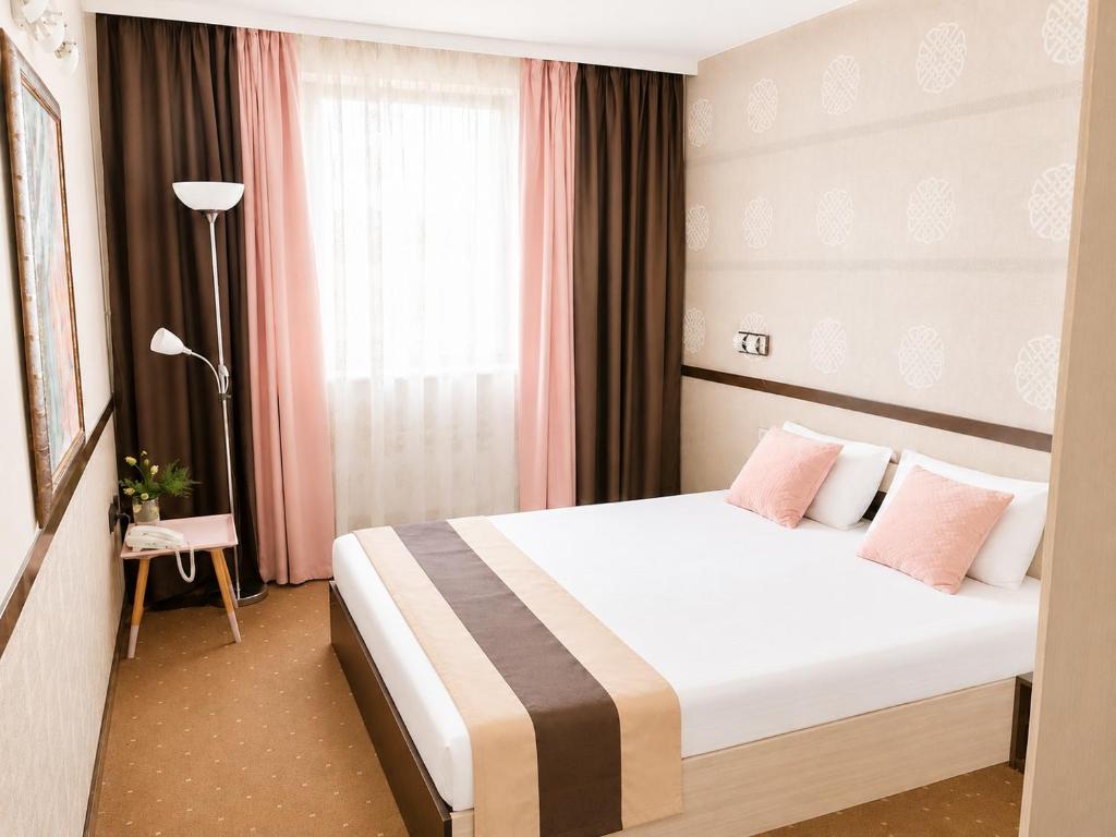 a hotel room with a large bed with pink pillows at Hotel Rostov in Pleven