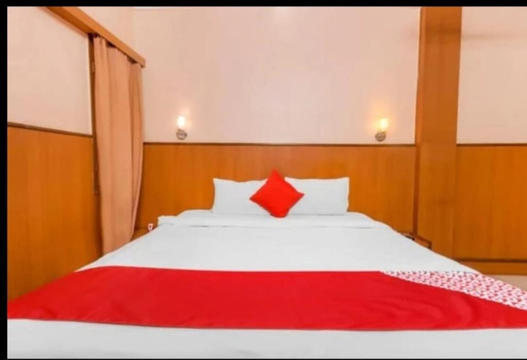 a bedroom with a white bed with a red pillow at HOTEL Embassy in Rānchī