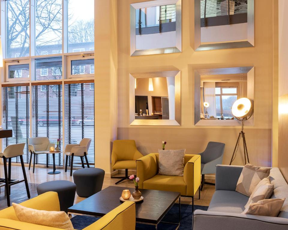 a waiting room with yellow furniture and windows at PLAZA INN Hamburg Horner Rennbahn in Hamburg