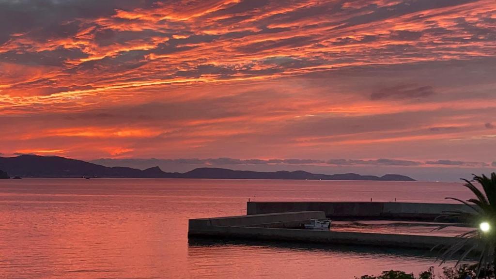 a sunset over a body of water with a dock at スパイス平戸 in Hirado