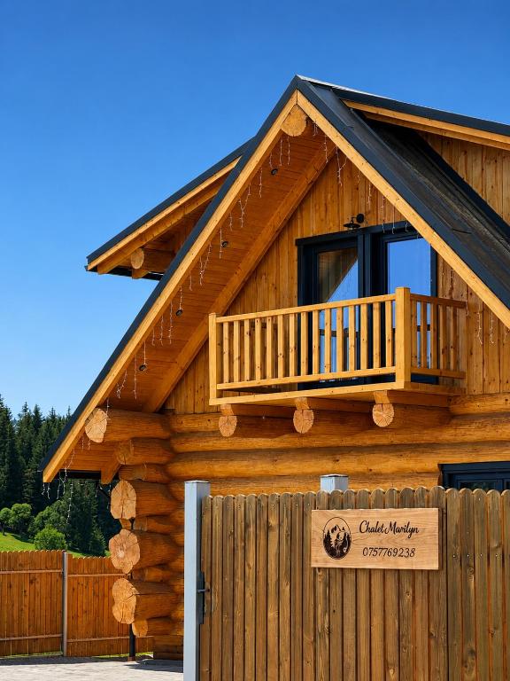 a log cabin with a balcony and a fence at Chalet Marilyn in Topliţa