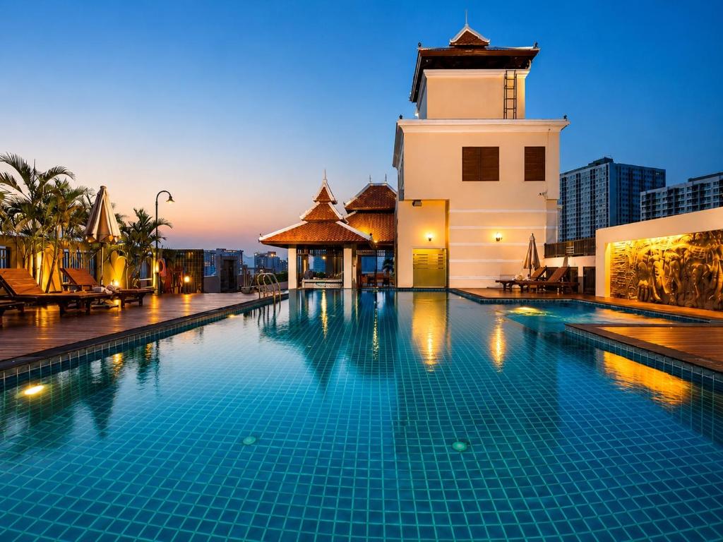 a swimming pool in front of a building with a clock tower at Aiyara Palace in North Pattaya