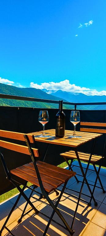 a wooden table and chair with wine glasses on a balcony at ValtellinaHome in Villa di Tirano