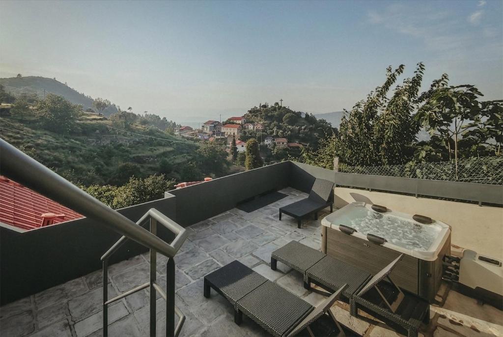 a balcony with a hot tub and chairs at Abrigos do Castelo in Carvalho de Rei