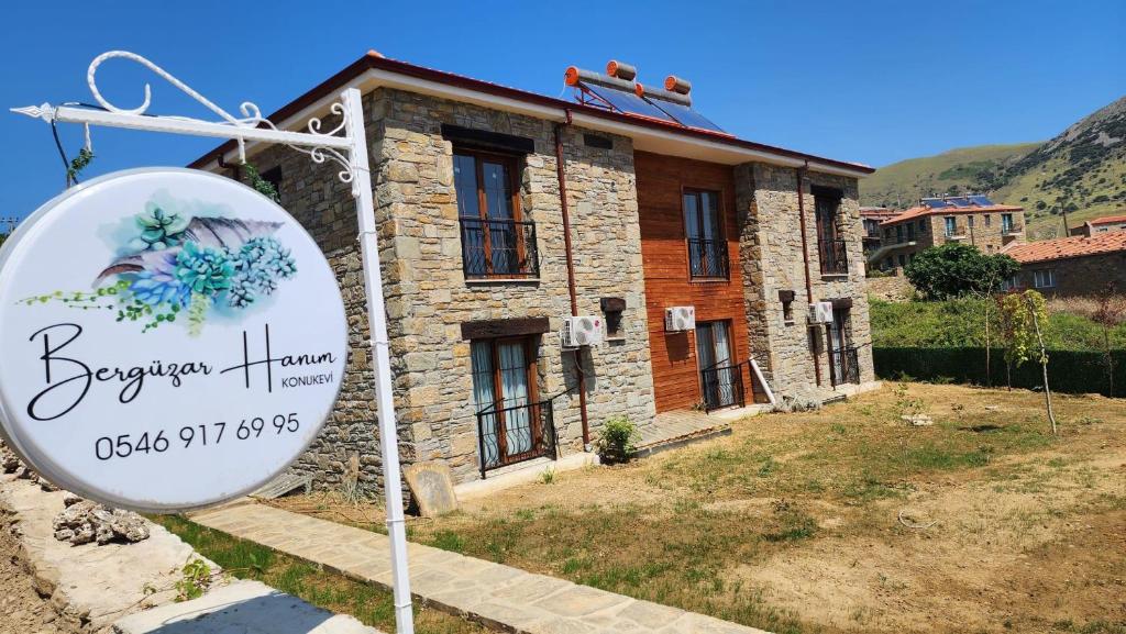 a sign in front of a building with a house at Bergüzar Hanım Konukevi in Gokceada Town