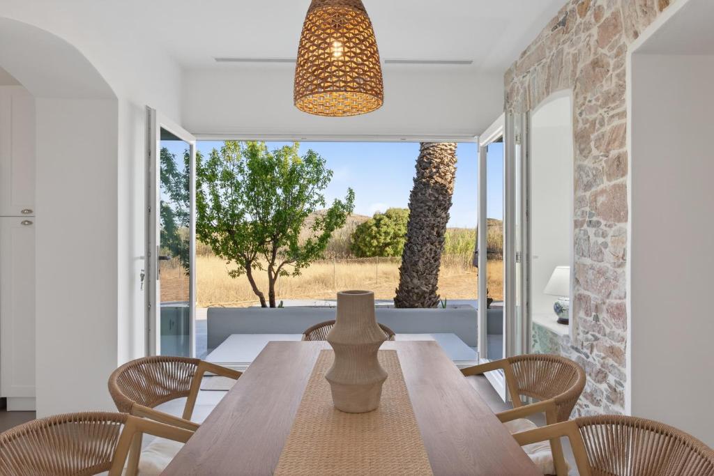 a dining room with a table and chairs and a window at Celeste Syros Retreat in Vári