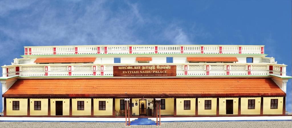 a large white building with a red roof at Pattiah Naidu Palace in Palni