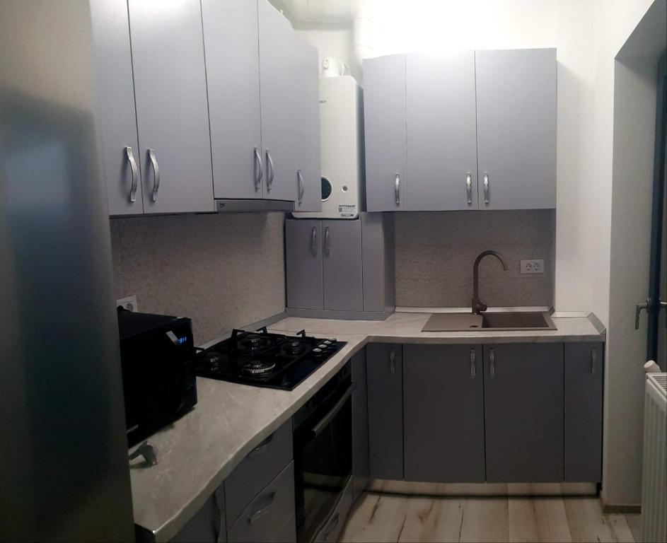 a kitchen with white cabinets and a stove and a sink at Studio zona centrala in Craiova