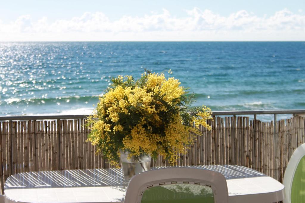 uma mesa com um vaso de flores na praia em Les Pieds dans l'Eau em La Croix-Valmer