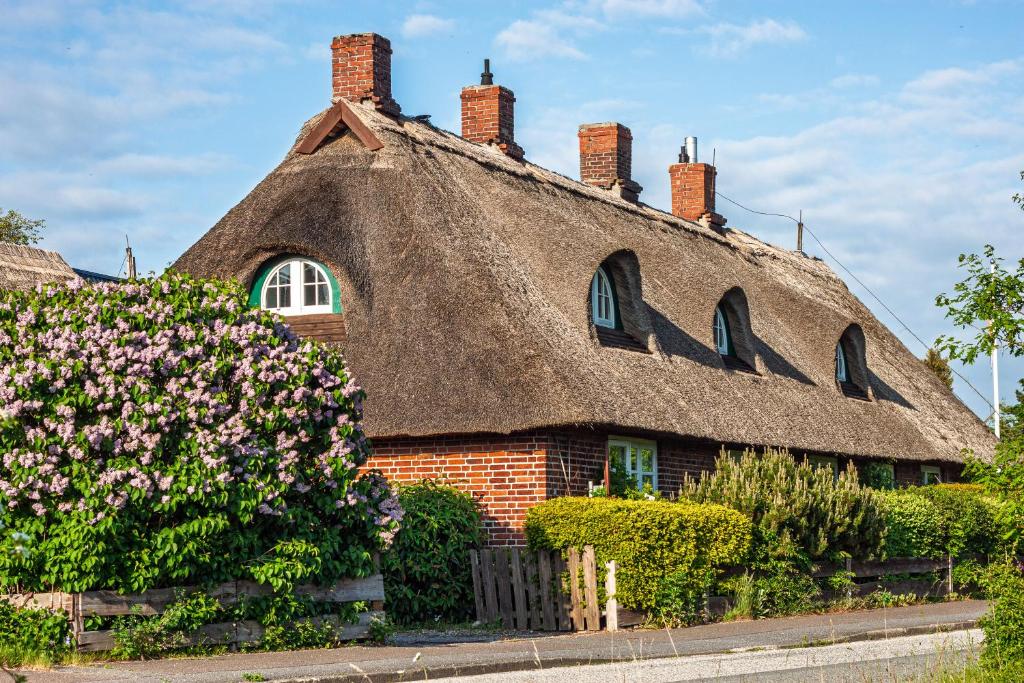 a thatched house with flowers in front of it at Reethaus Beusloe II in Beusloe